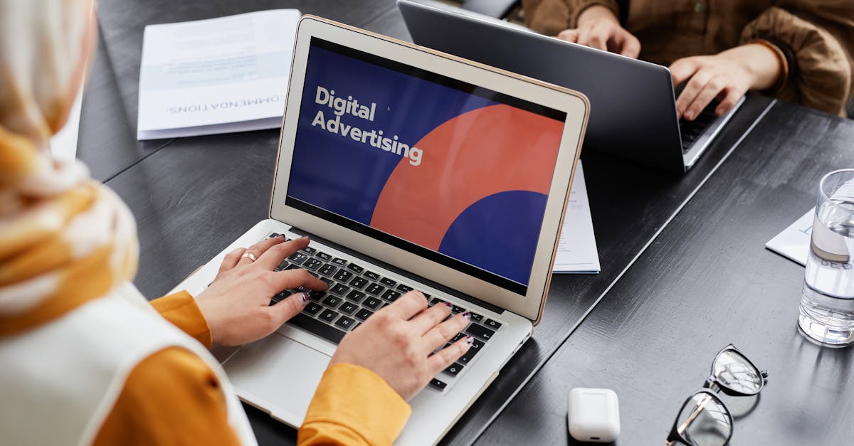 Two professionals work on laptops focusing on digital advertising in an office setting.